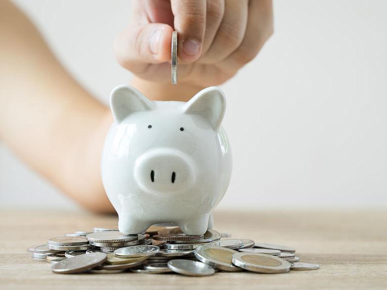 A piggy bank with a hand dropping coins inside